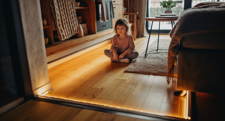 Kind sitzt im warmen Wohnzimmer auf dem Boden