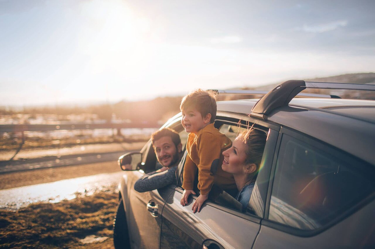 Frau und Kind schauen bei Sonnenuntergang aus dem Auto